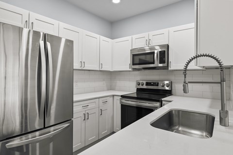 A kitchen with a stainless steel refrigerator, microwave, oven, and sink.