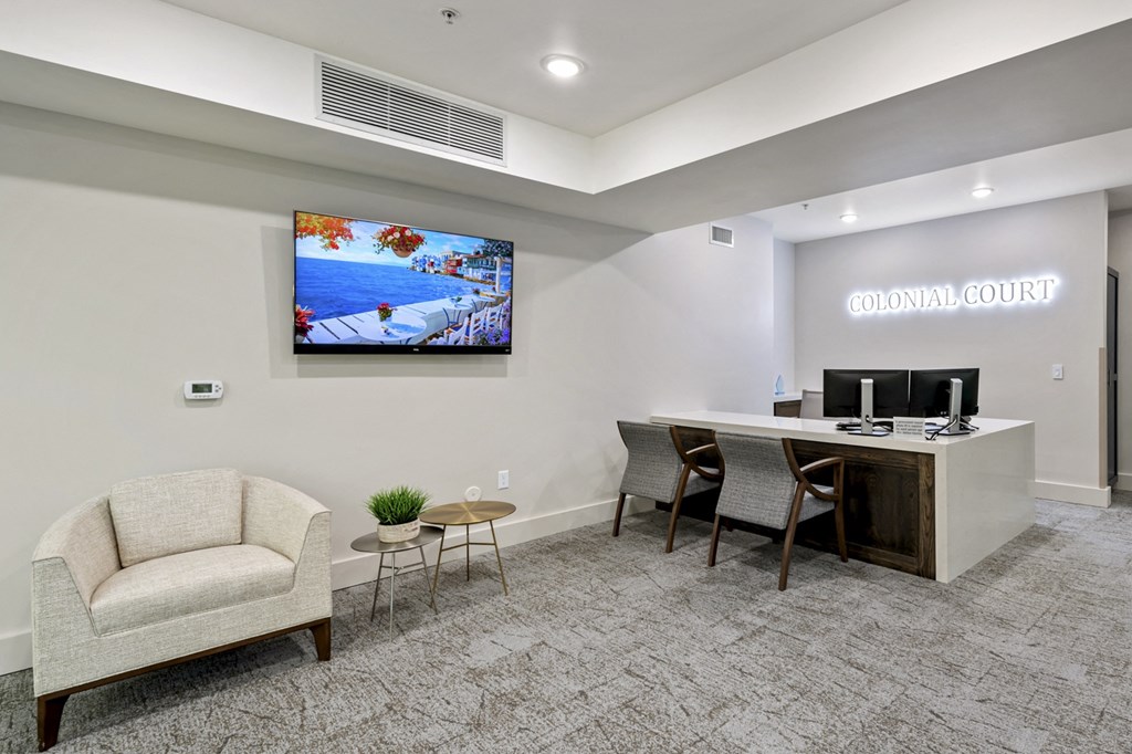a room with a desk and chairs and a tv on the wall