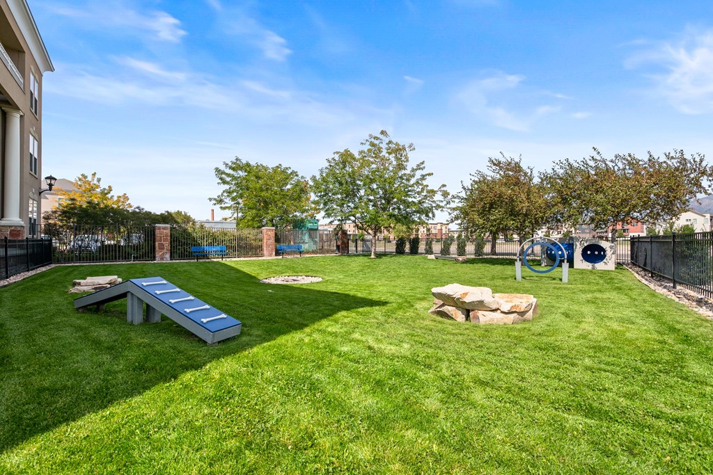 A park with a slide, a rock, and a bench.