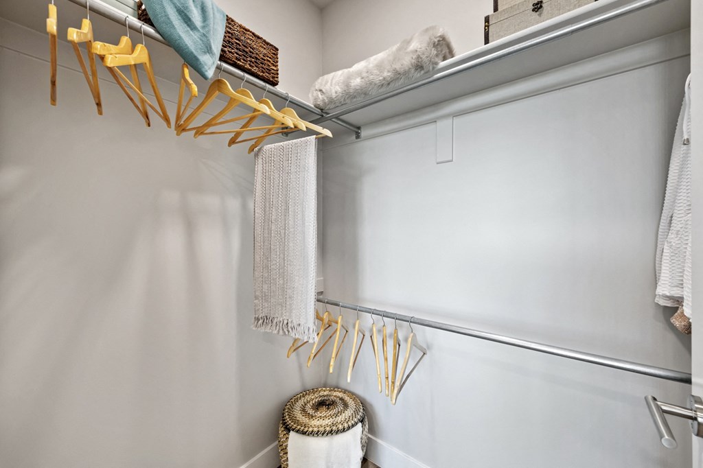 a walk in closet with grey walls and a white closet door with yellow hooks