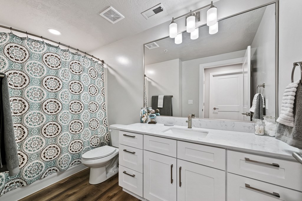 a bathroom with a large mirror and a shower with a blue and white pattern