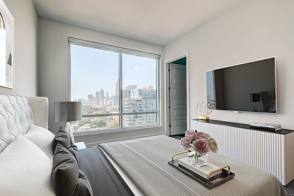 a bedroom with a bed and a large window and a tv