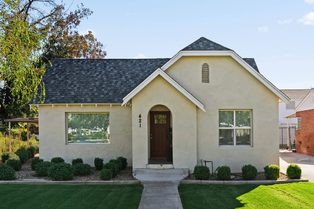 A small house with a brown door and windows surrounded by greenery.