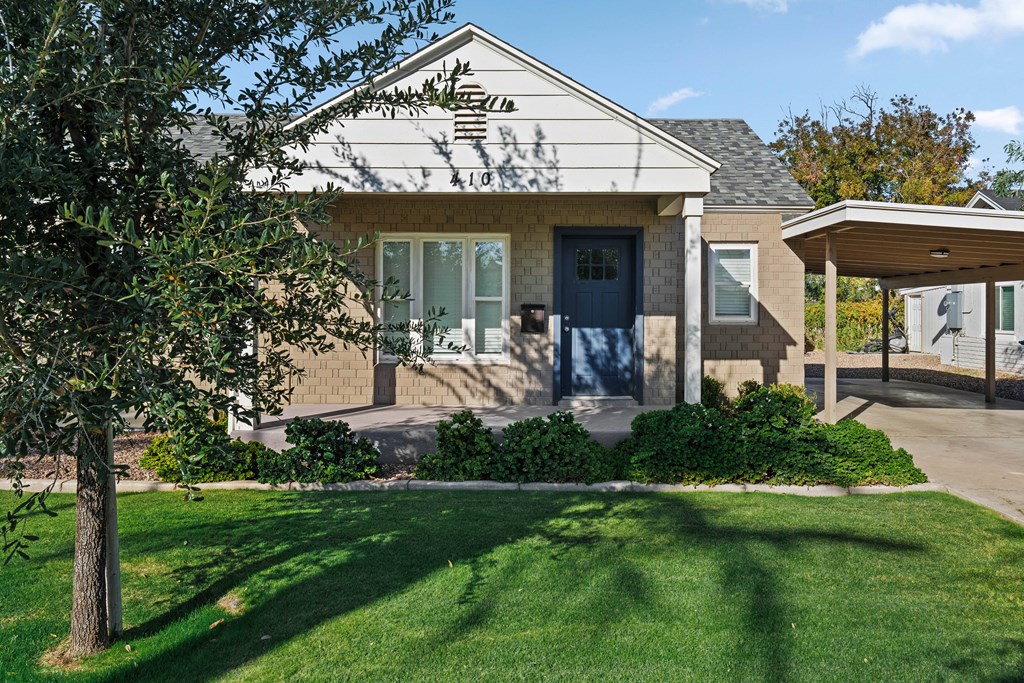 A house with a blue door and a tree in front.