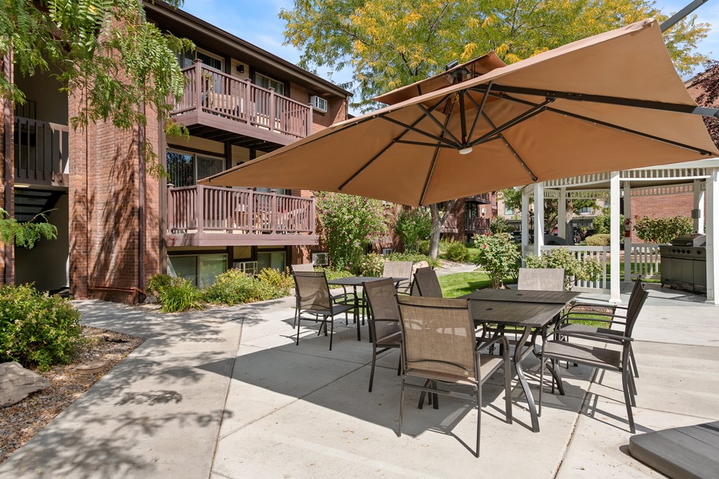 A patio with a table and chairs under an umbrella.