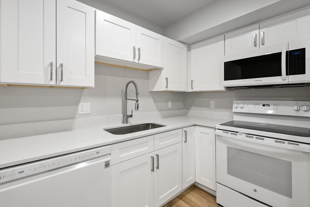 A white kitchen with a black microwave.