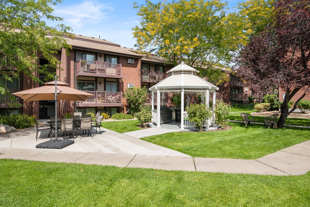 A gazebo is in the middle of a grassy area in front of an apartment building in salt lake city utah