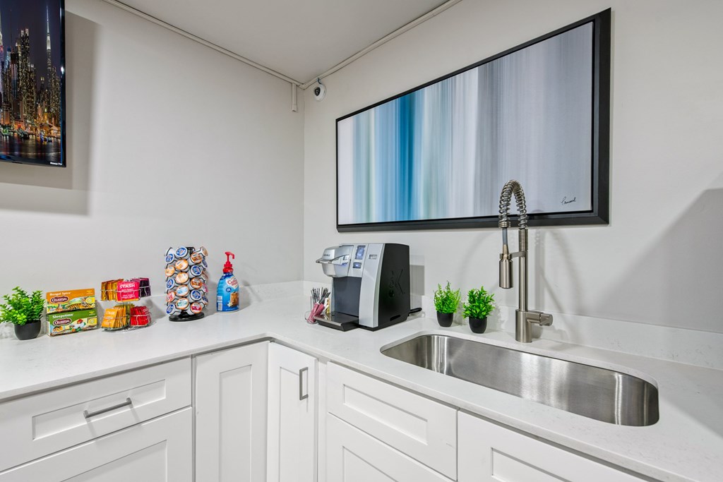A kitchen with a sink, a microwave, and a TV mounted on the wall.