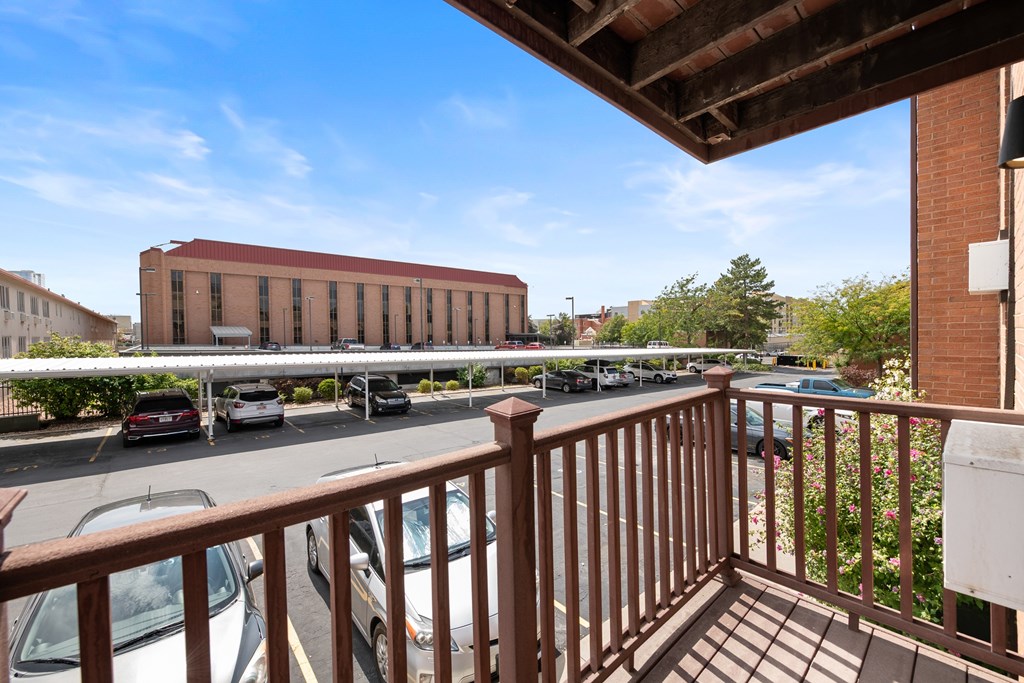 A view from a balcony overlooking a parking lot and a building.