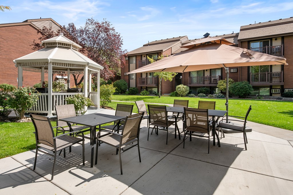 A patio with a table and chairs and a gazebo.