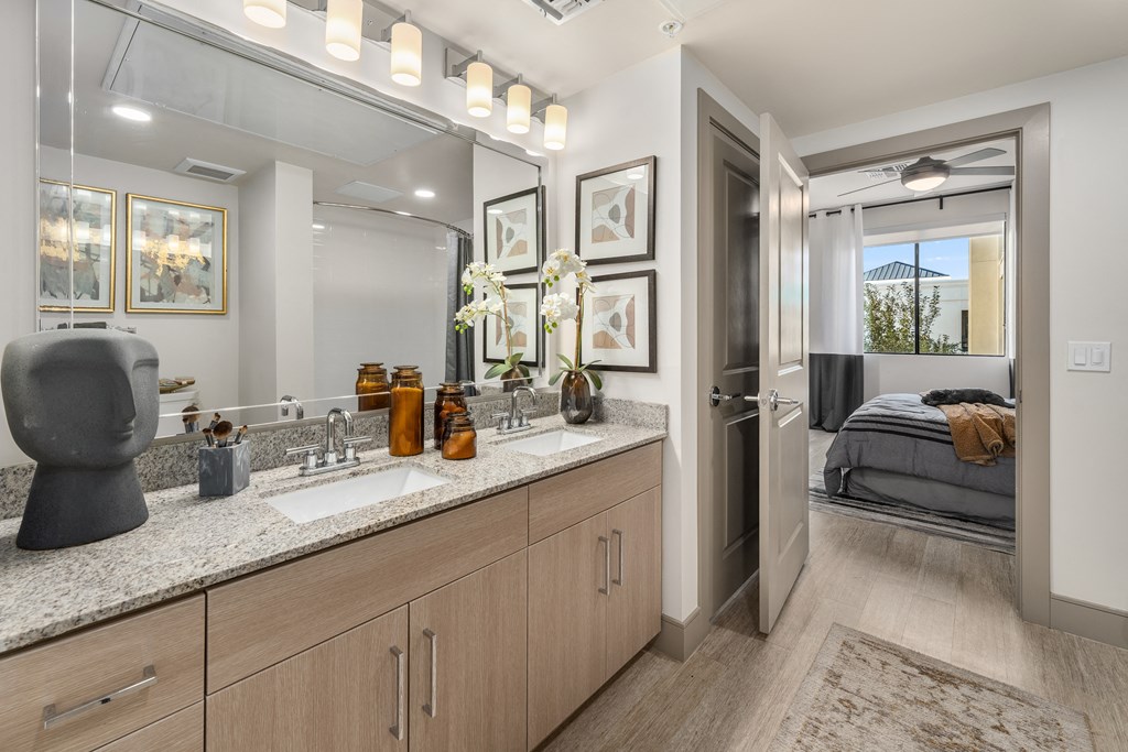 a bathroom with a sink and a mirror and a door to a bedroom