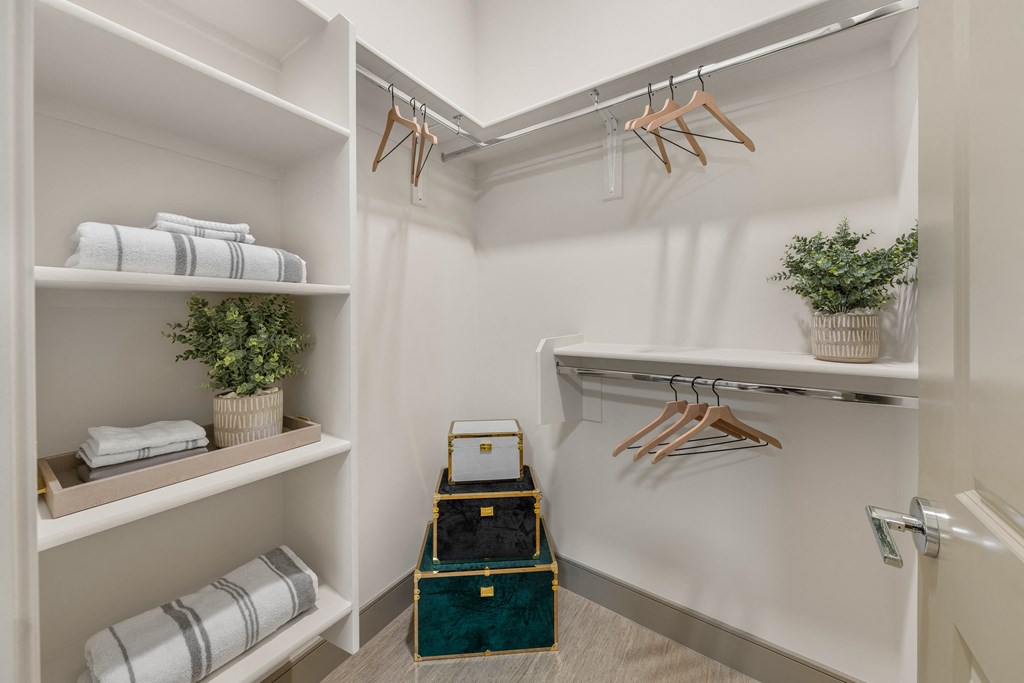 a walk in closet with folded towels and a luggage cart
