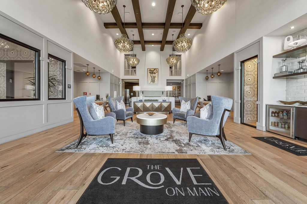 a living room with blue chairs and a rug that reads the grove on man