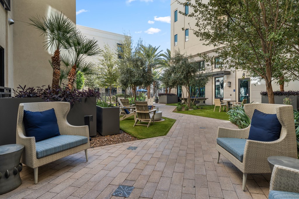 a courtyard with chairs and tables and a building in the background