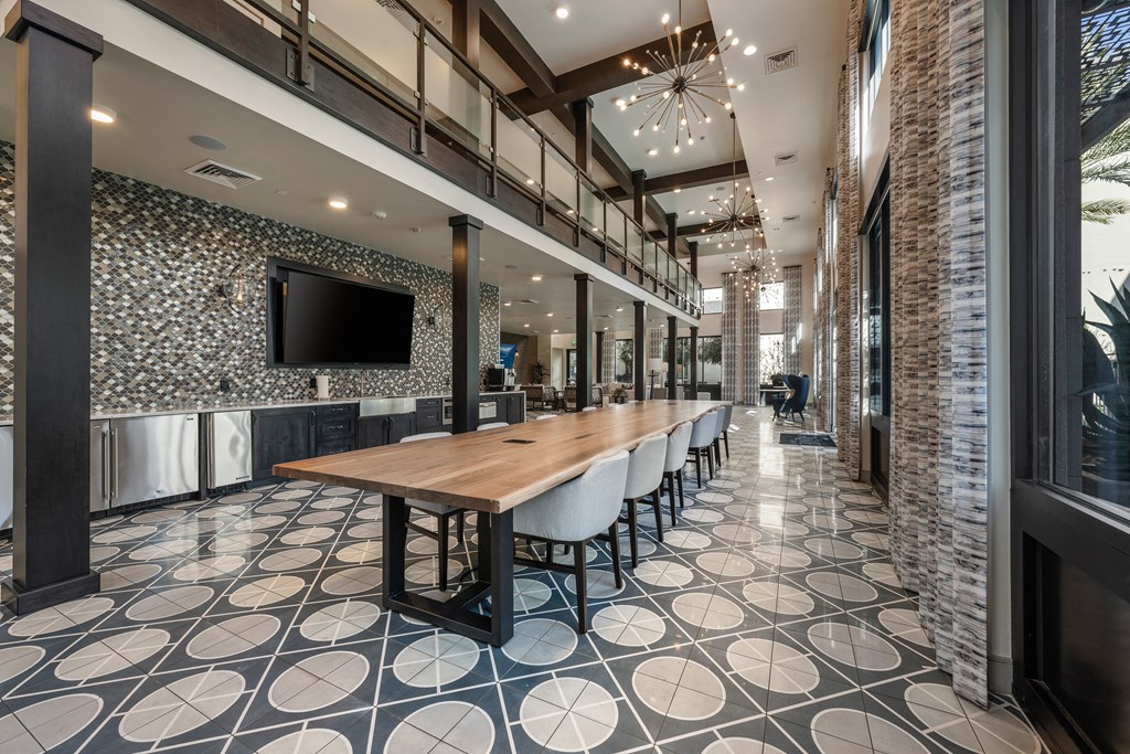 a communal table in a lobby with chairs and a television