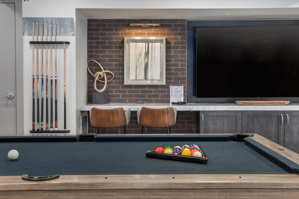 a pool table and a tv in a room with a brick wall