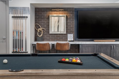 a pool table and a tv in a room with a brick wall