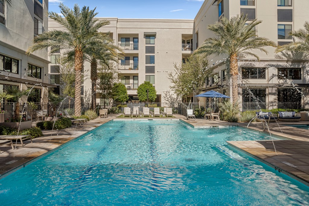 a swimming pool with palm trees and a building in the background