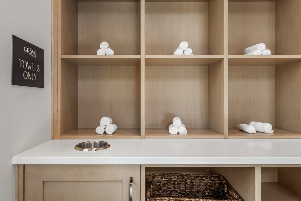a bathroom with a white counter and shelves with