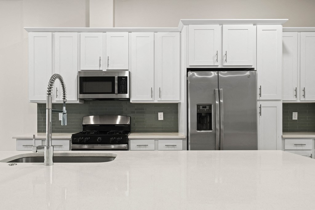 A kitchen with white cabinets and a stainless steel refrigerator.
