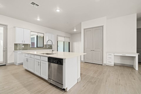 A modern kitchen with white cabinets and a wooden floor.