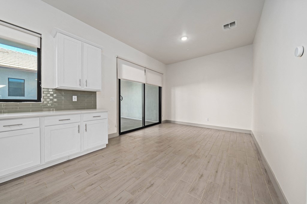 A kitchen with white cabinets and a wooden floor.