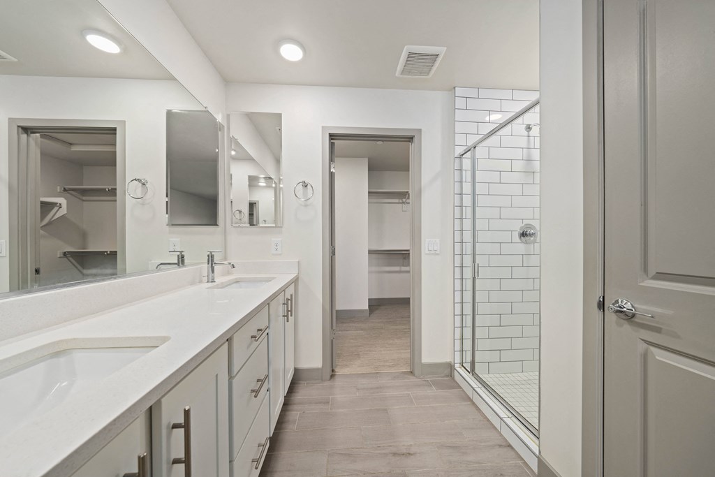 A bathroom with a walk-in shower and double sinks.