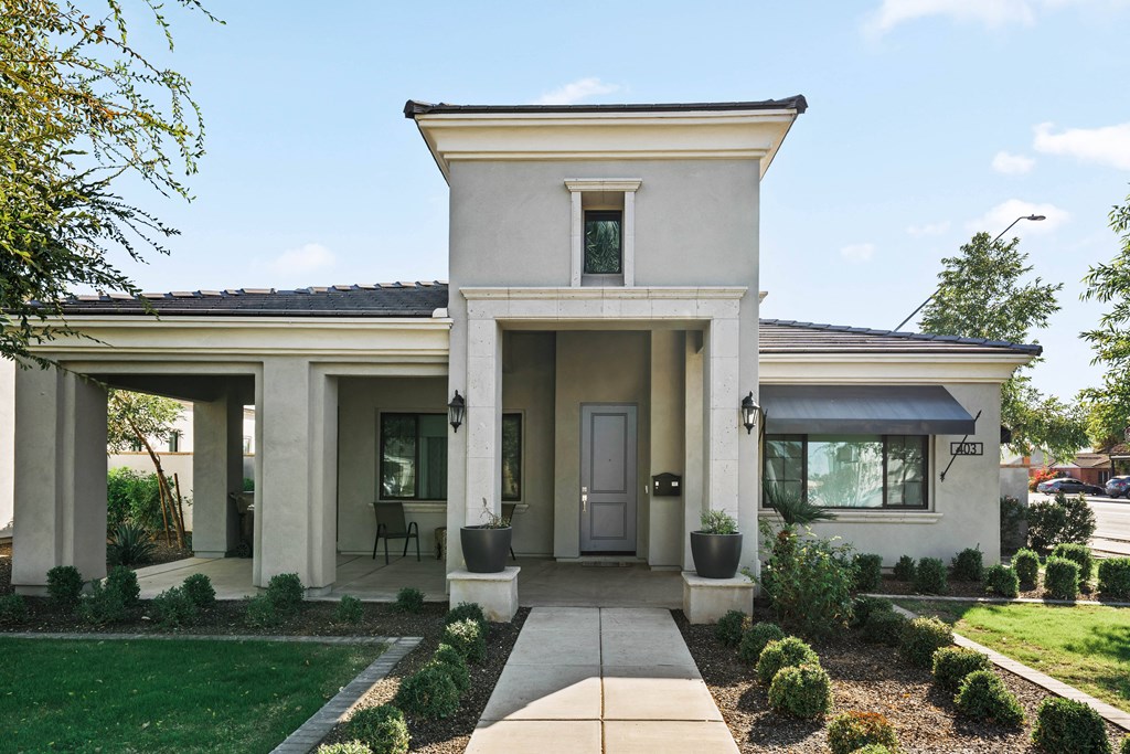A white house with a black roof and a grey awning.