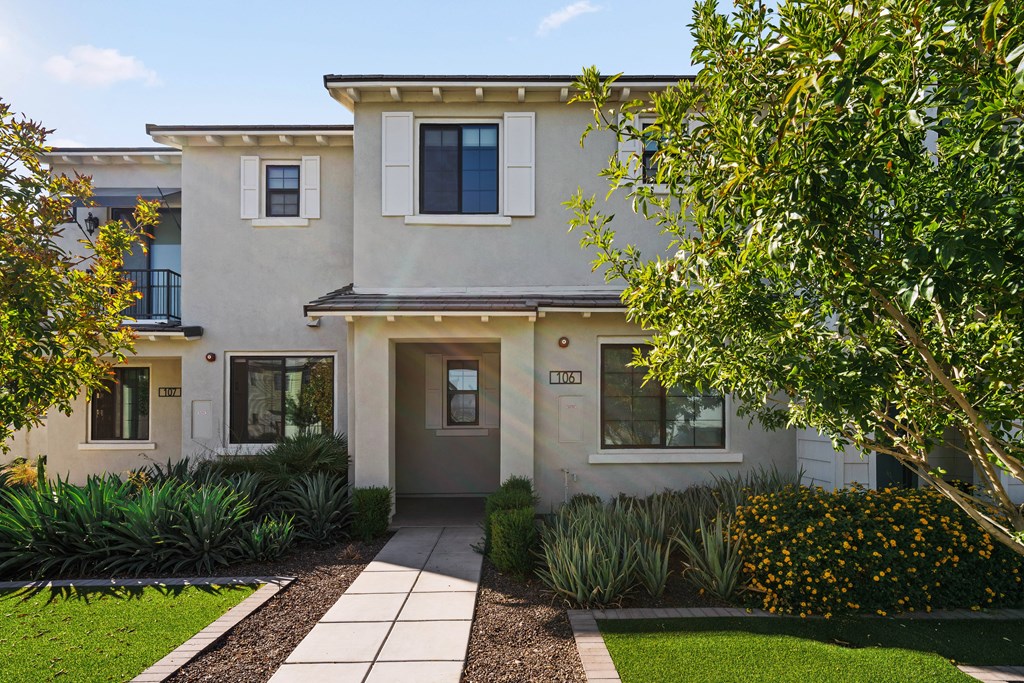 A modern house with a grey front door and a small garden in front.