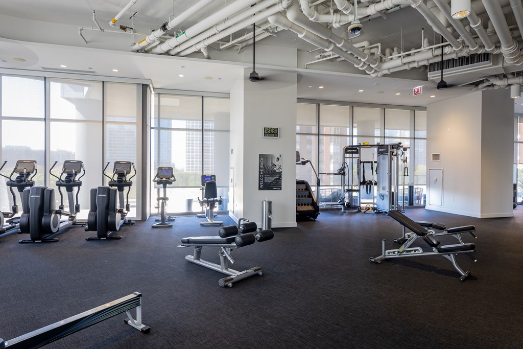 A gym with a variety of equipment including treadmills, weights, and exercise machines.