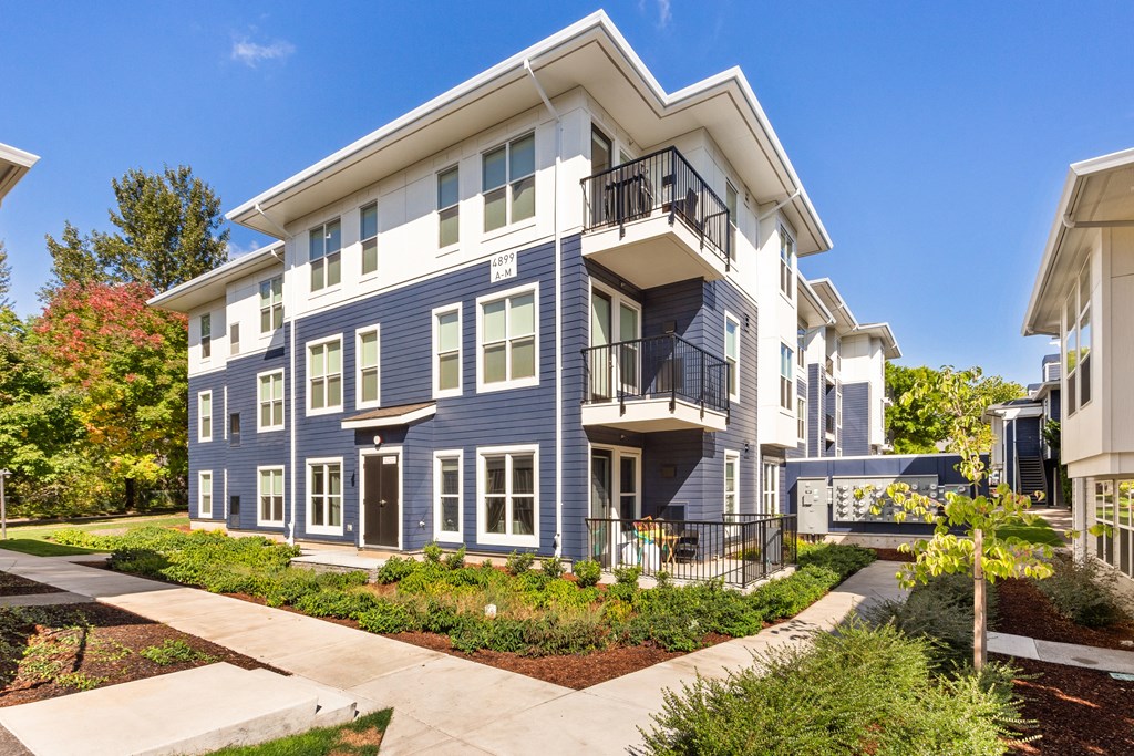 A blue and white two story apartment building with a balcony on the second floor.