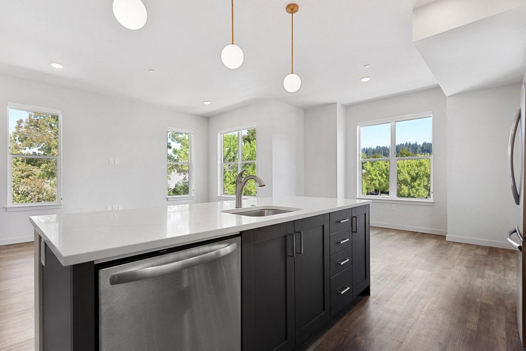 the kitchen has a large island with a sink and plenty of windows