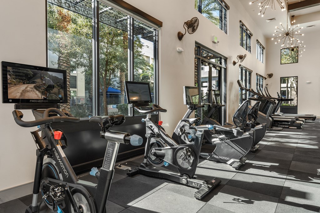 a gym with treadmills and other exercise equipment in a building with large windows