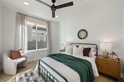 A bedroom with a bed, a chair, and a ceiling fan.