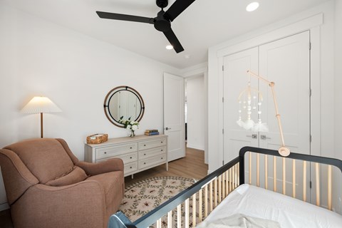 A baby's room with a crib, a chair, and a dresser.