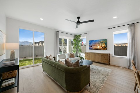A living room with a green couch and a ceiling fan.