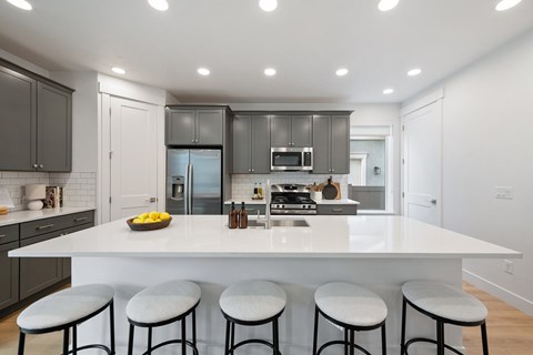 A modern kitchen with a white island and bar stools.