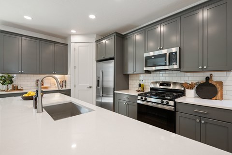 A modern kitchen with a white countertop and dark grey cabinets.