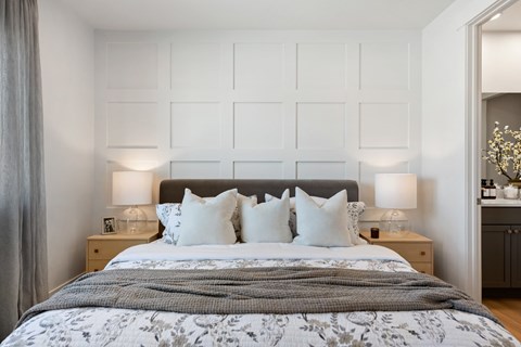 A bed with a grey comforter and four white pillows is in the image.