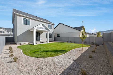 A modern house with a grey exterior and a gravel driveway.