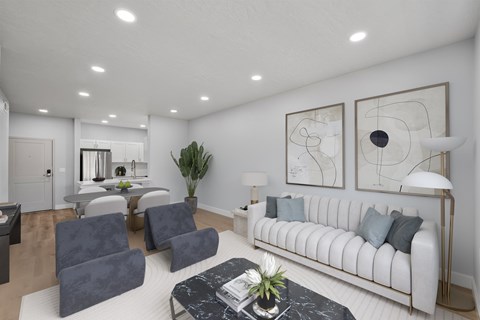 A living room with a white couch, grey chairs, and a coffee table with a plant on it.