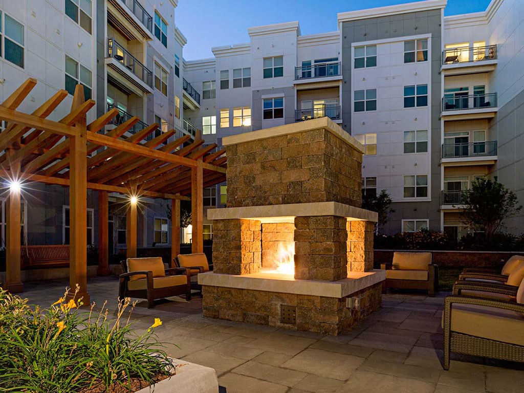 View of courtyard fireplace at night with Atmark apartments in background