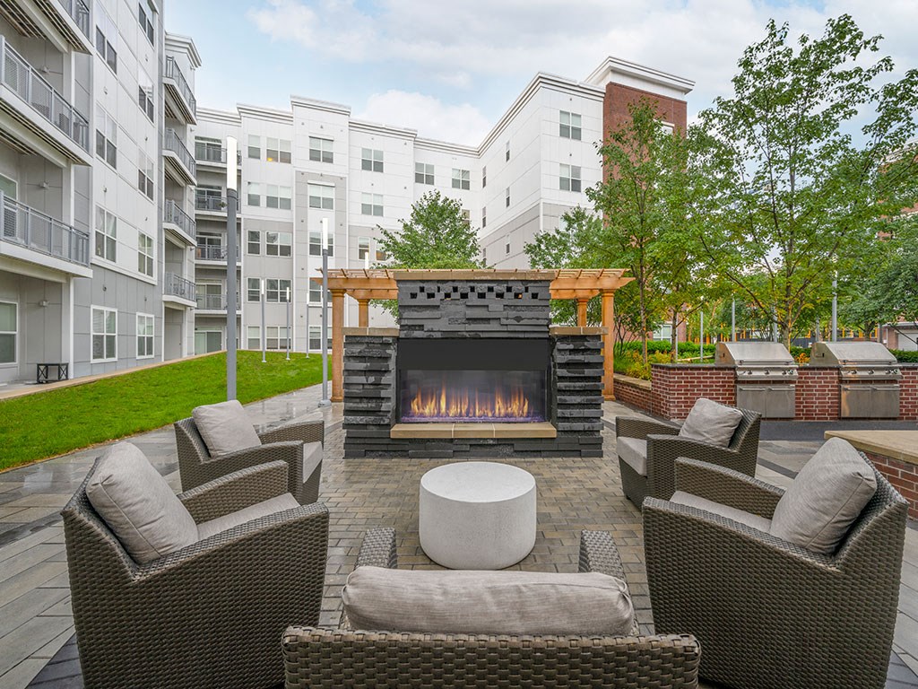 a patio with furniture and a fireplace in front of an apartment building