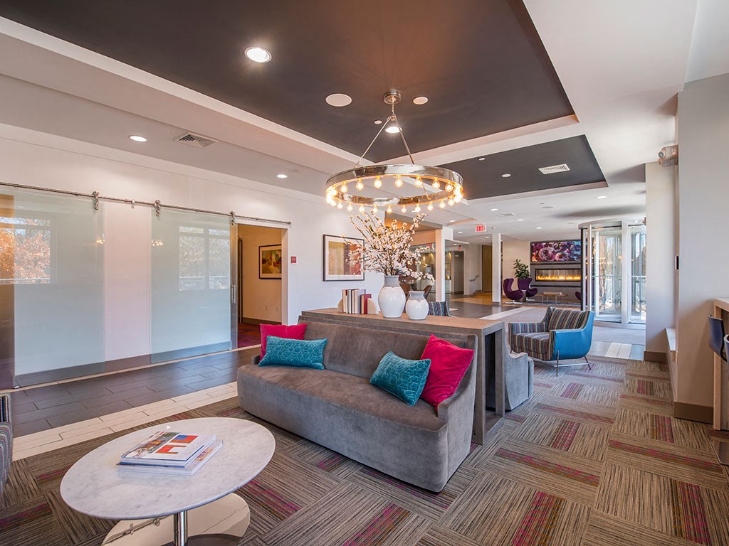 a lobby with a couches, coffee tables, and view of two private work from home rooms