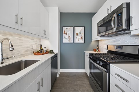 A modern kitchen with white cabinets and a black stove top oven.