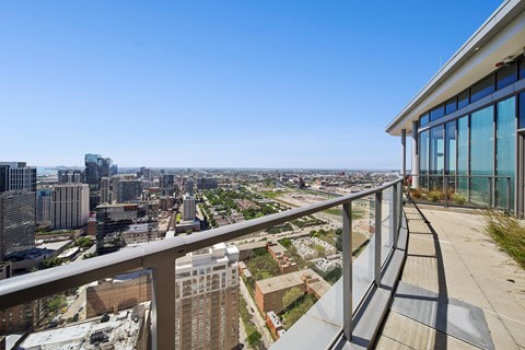 A balcony overlooks a cityscape with buildings and greenery.