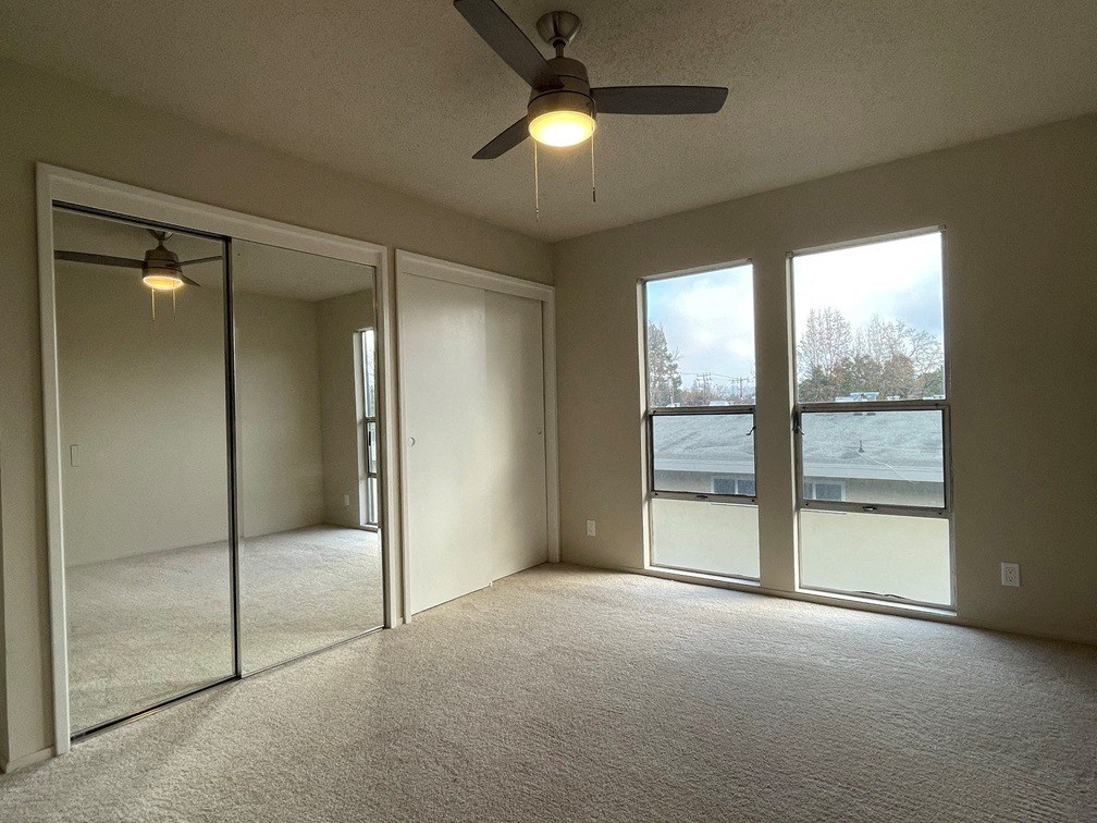 Cozy bedroom with plush carpet, mirrored closet doors, and large vindows at 3543 Brook Street in Lafayette, CA 94549