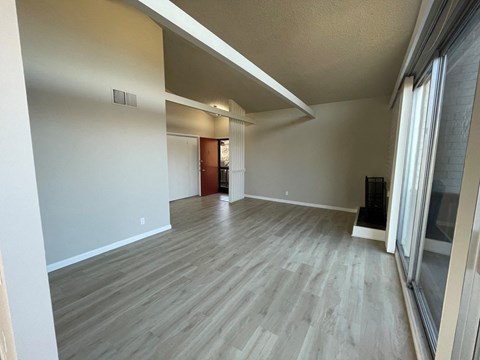 an empty living room with wood flooring and a large window