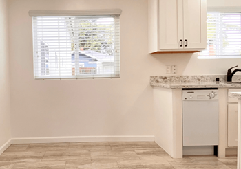 Open Space Kitchen and Dining Room with Two Large Windows, a Dishwasher, and Elegant White Cabinetry at Jefferson Street Apartments in Santa Clara, CA