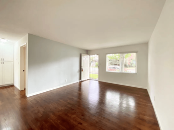 a bedroom with hardwood floors and white walls
